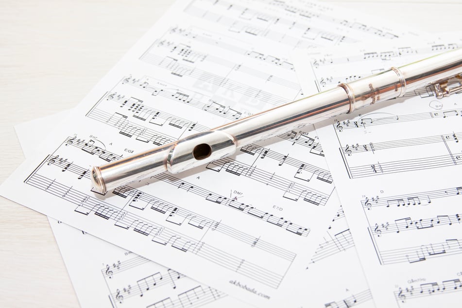 Close-Up Photo of Music Sheets with Silver Flute